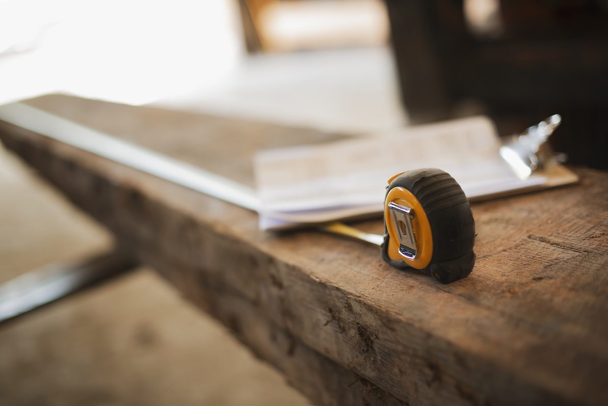 A tape measure resting on a board used to outline a DIY deck construction.